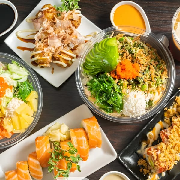 Overhead view of various Poki Yaki dishes, including poke bowls, sushi, and takoyaki.